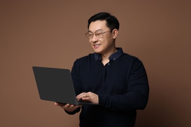 Portrait of happy man with laptop on brown background