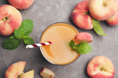 Natural peach juice and fresh fruits on grey table, flat lay