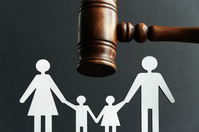 Divorce concept. Paper figures of family and wooden gavel on black background