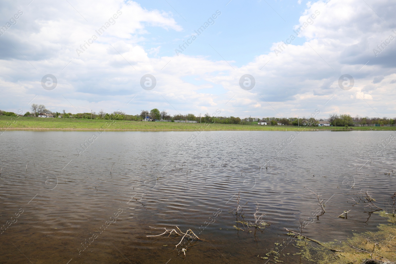 Photo of River near village under sky with clouds. Picturesque landscape