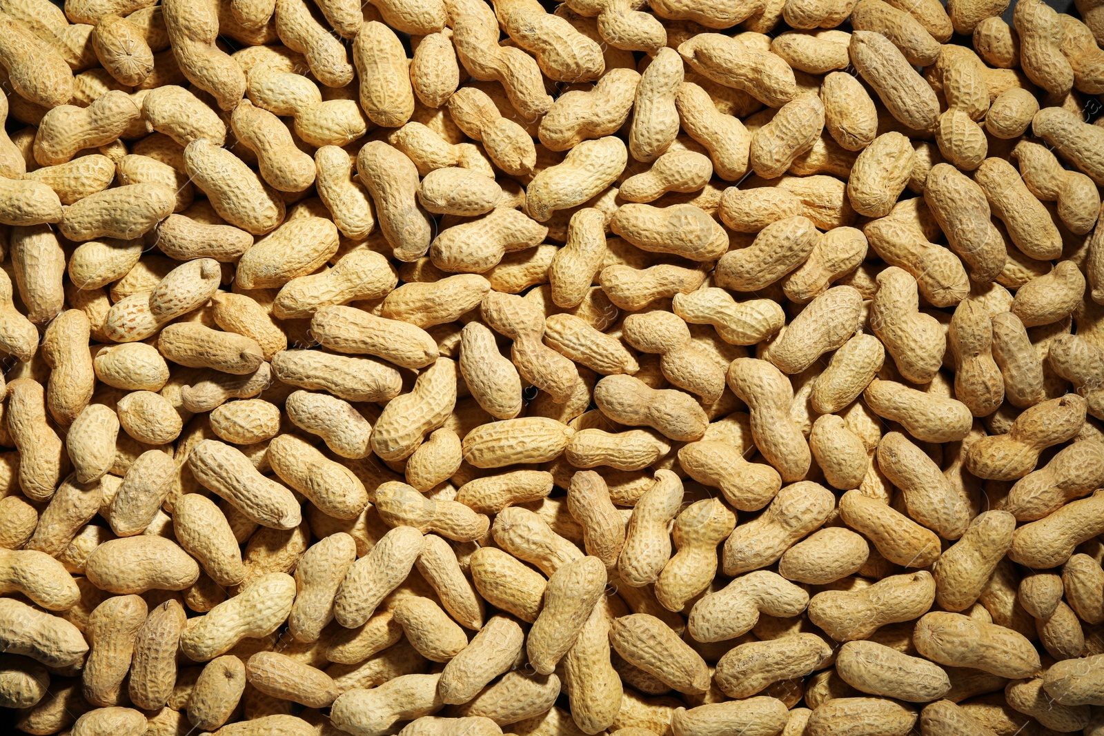 Photo of Many fresh unpeeled peanuts as background, top view