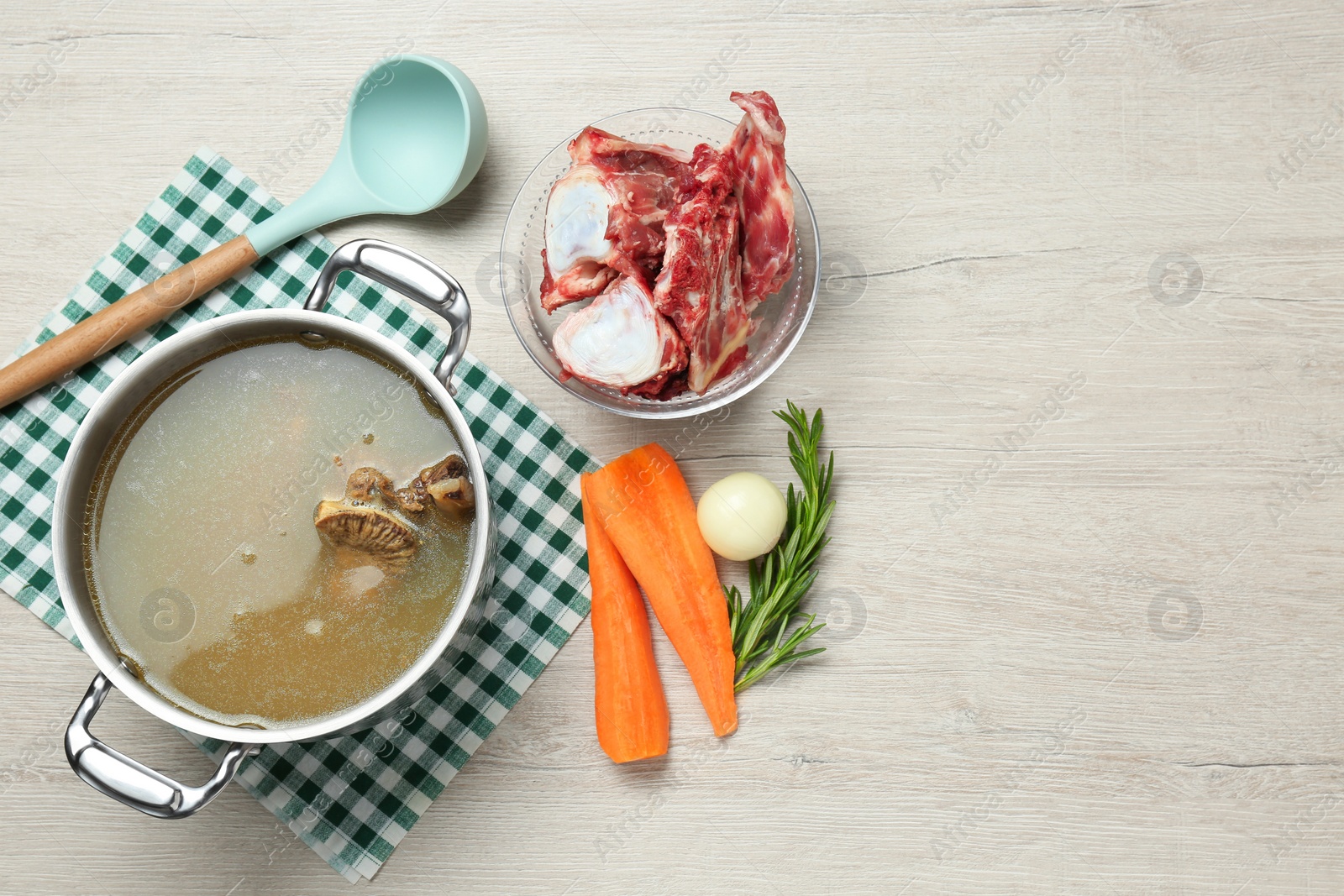 Photo of Delicious homemade bone broth and ingredients on white wooden table, flat lay. Space for text