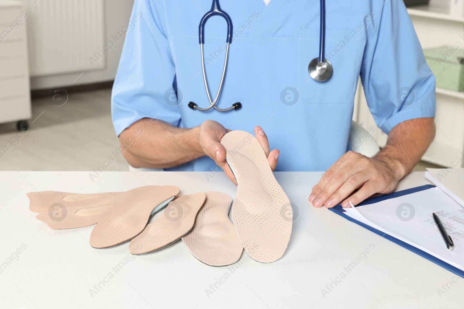 Photo of Male orthopedist showing insoles in hospital, closeup