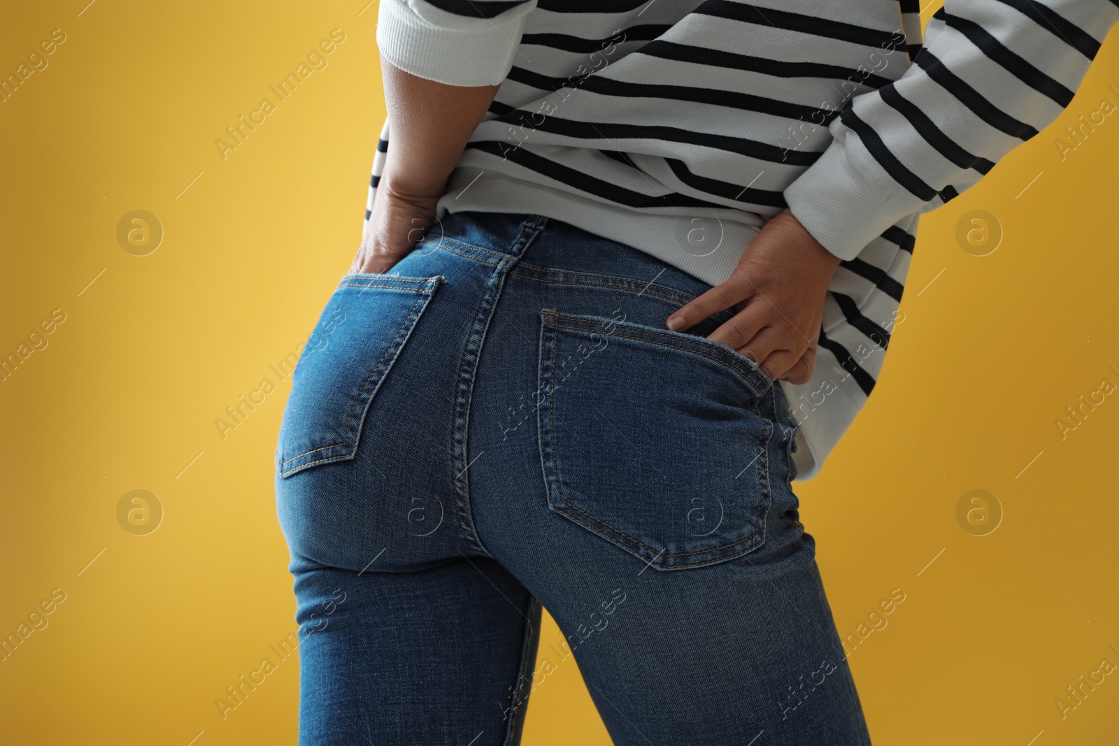 Photo of Woman wearing jeans on yellow background, closeup