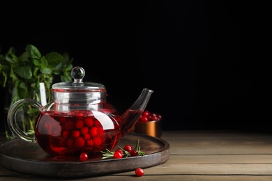 Photo of Tasty hot cranberry tea and fresh ingredients on wooden table. Space for text