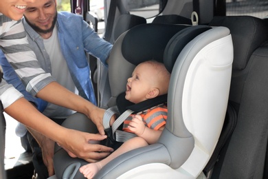 Photo of Mother fastening baby to child safety seat inside of car