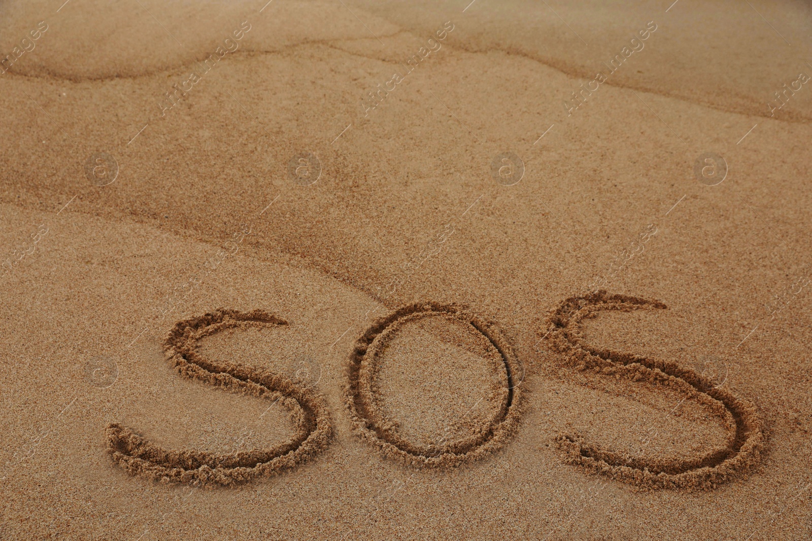 Photo of Message SOS drawn on sandy beach, space for text