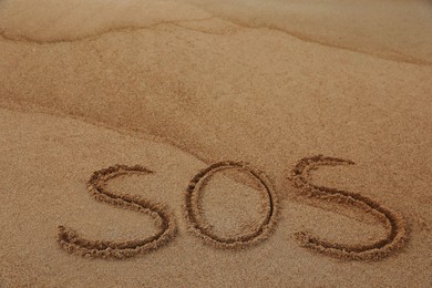 Photo of Message SOS drawn on sandy beach, space for text