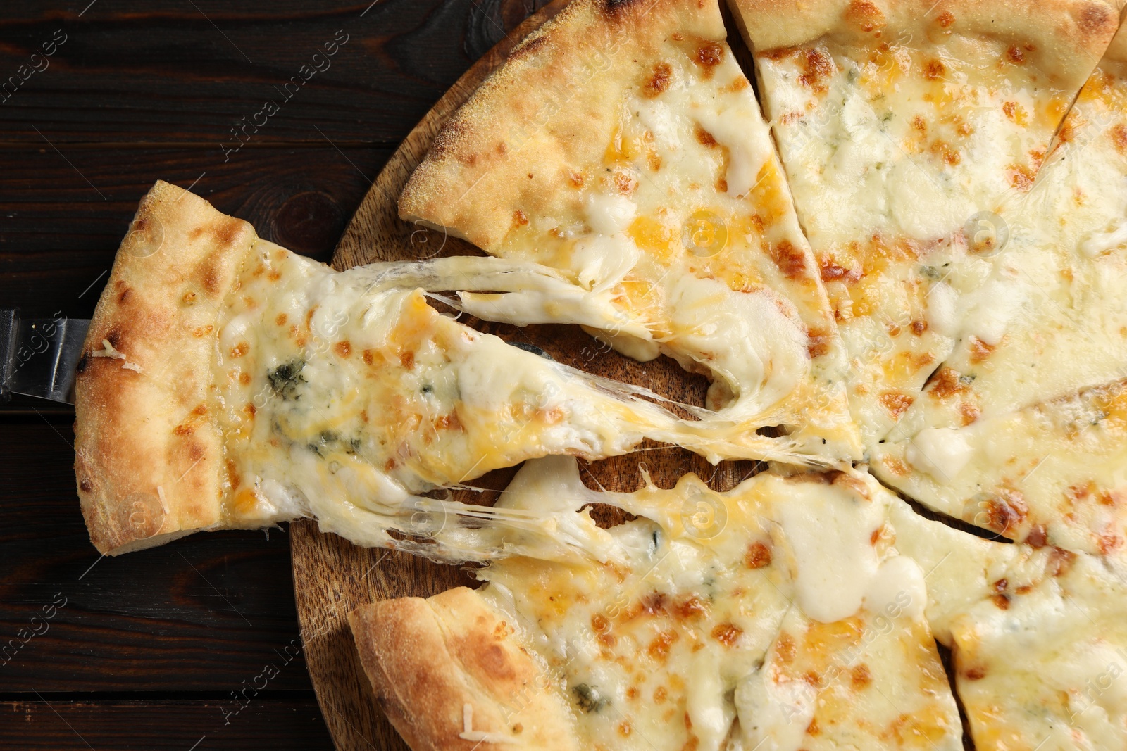 Photo of Delicious cut cheese pizza with server on wooden table, top view