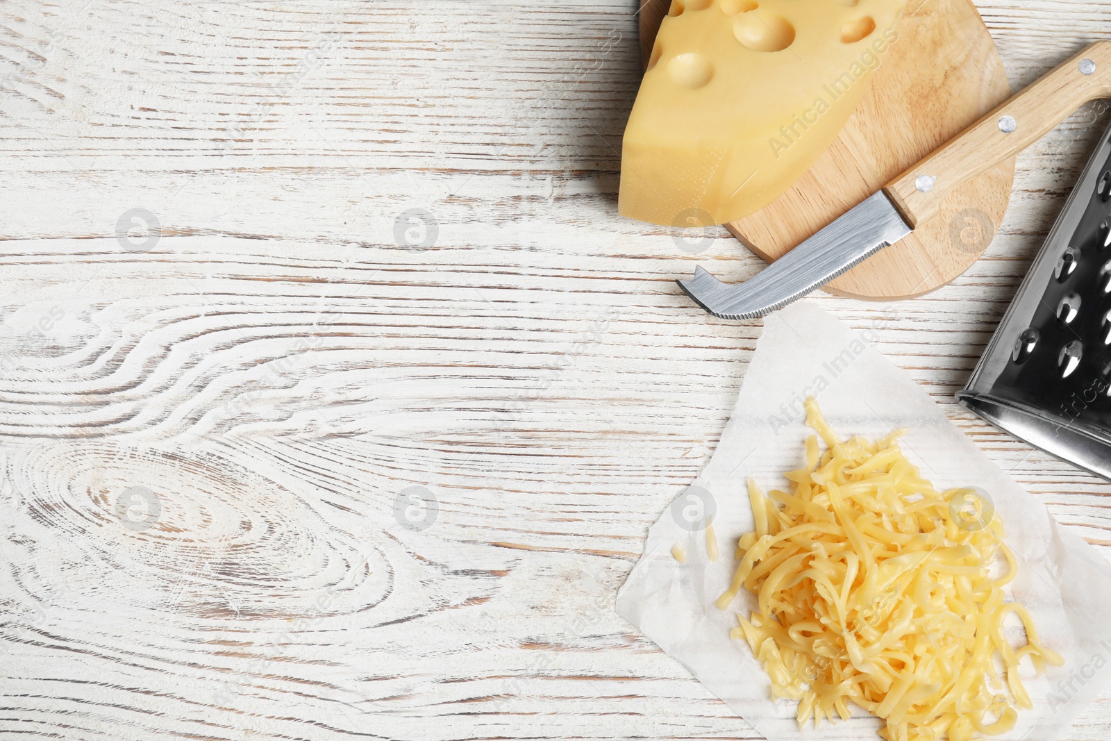 Photo of Tasty grated cheese on white wooden table, flat lay. Space for text