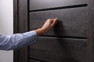 Photo of Woman knocking on door indoors, closeup view