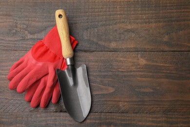 Gardening gloves and trowel on wooden table, top view. Space for text