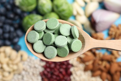 Wooden spoon of pills over foodstuff, top view. Prebiotic supplements