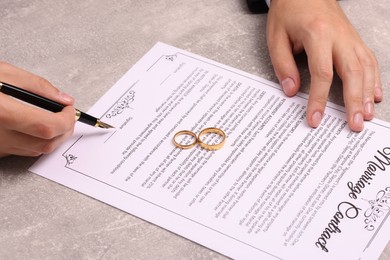 Photo of Man signing marriage contract at light grey table, closeup