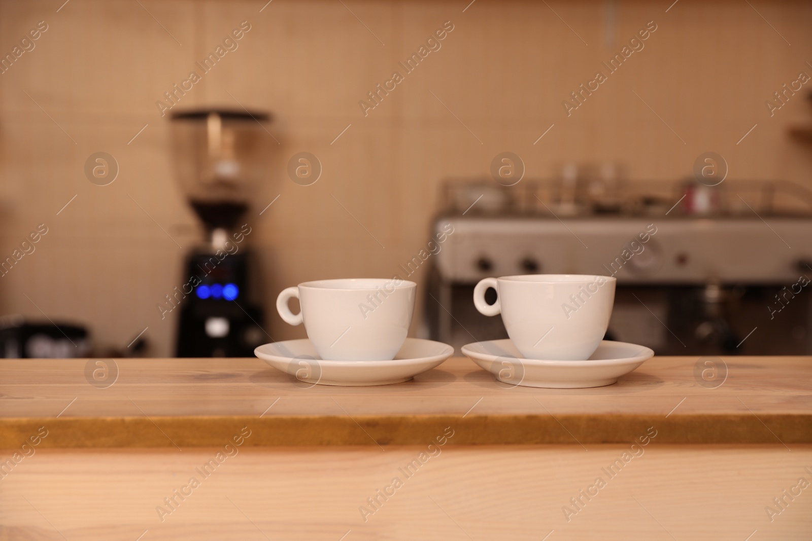 Photo of Cups of fresh aromatic coffee on table against blurred background