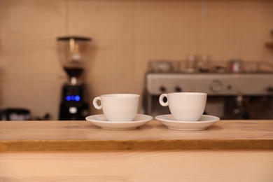 Cups of fresh aromatic coffee on table against blurred background