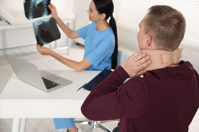 Photo of Doctor with neck MRI images consulting patient in clinic, space for text