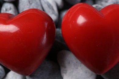 Photo of Red decorative hearts on grey stones, closeup