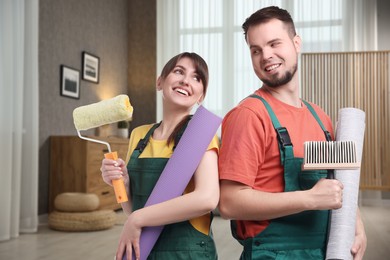 Workers with wallpaper rolls and tools in room