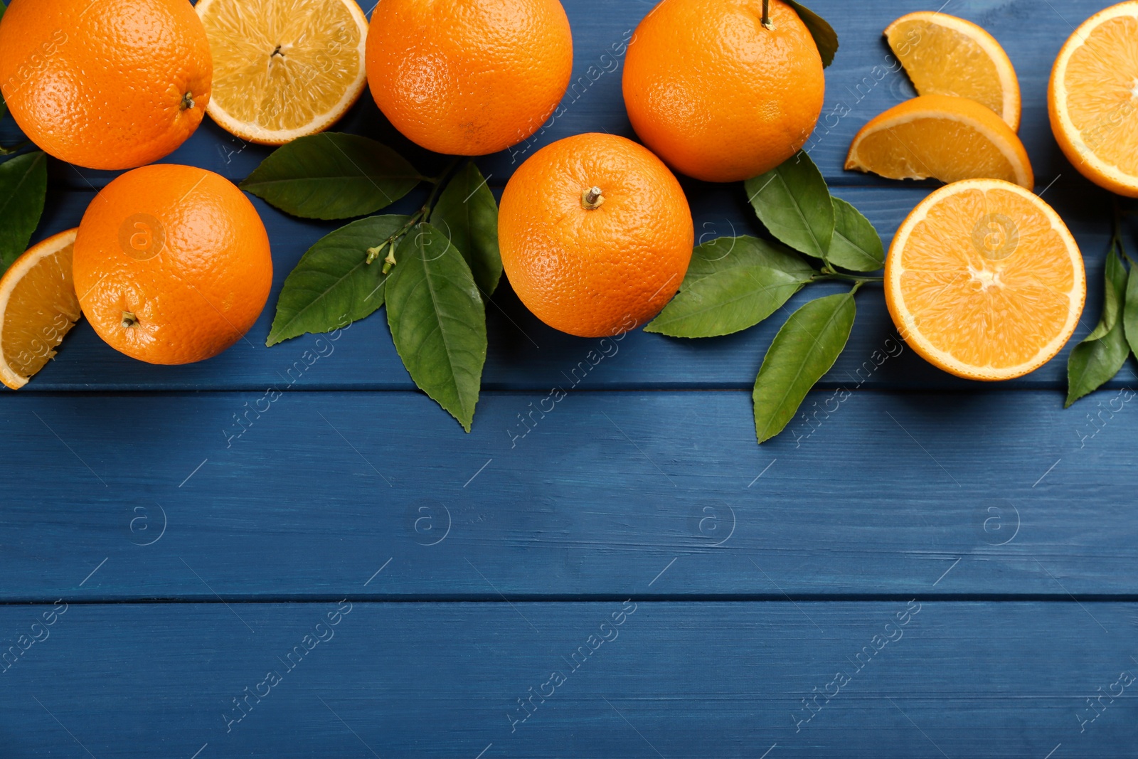 Photo of Delicious ripe oranges on blue wooden table, flat lay. Space for text