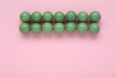 Photo of Many bright green gumballs on pink background, flat lay. Space for text