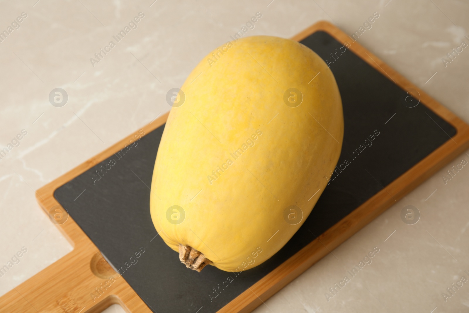 Photo of Board with whole ripe spaghetti squash on gray table