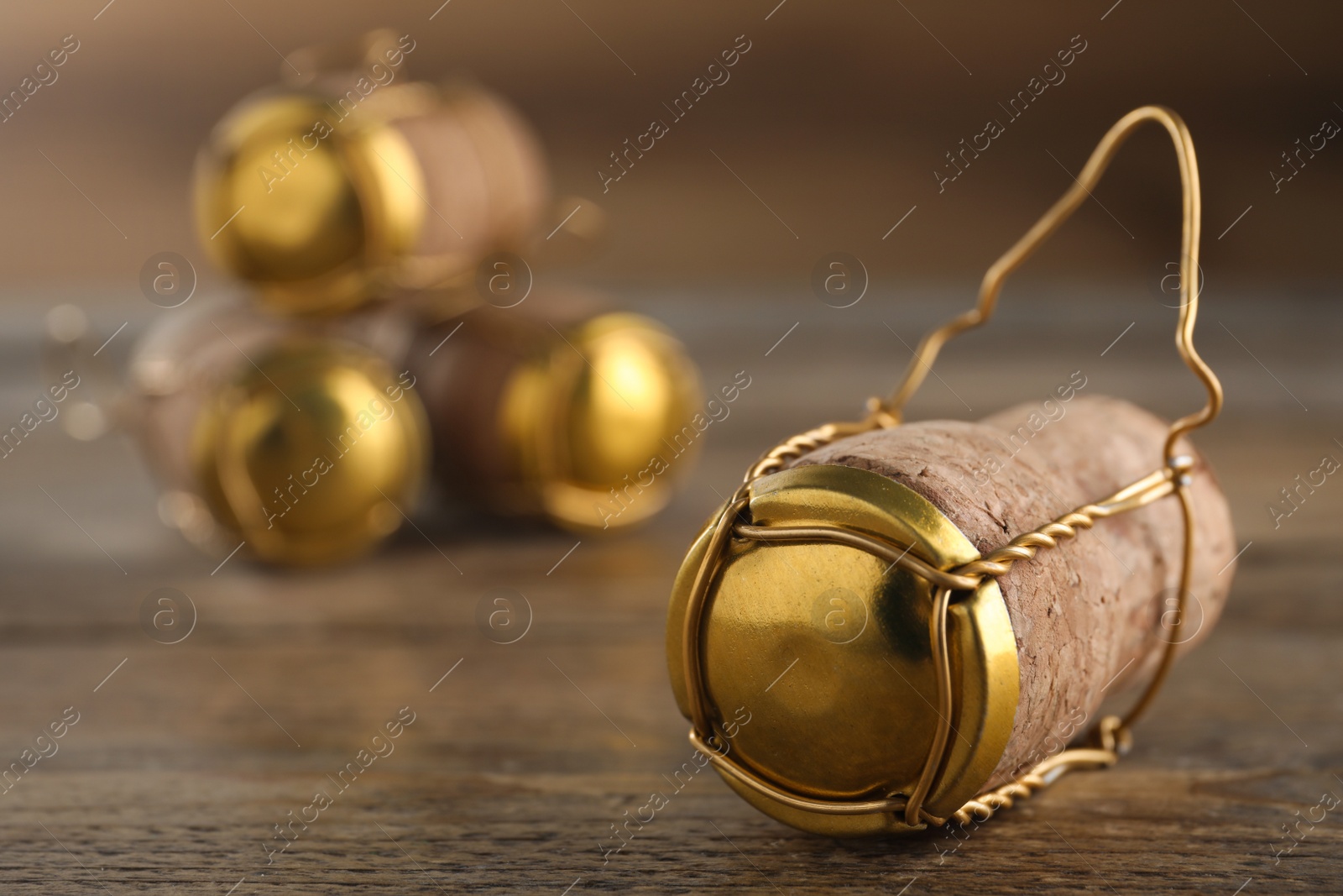 Photo of Cork of sparkling wine and muselet cap on wooden table, closeup. Space for text