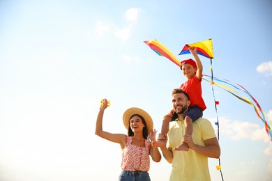 Happy parents and their child playing with kites on sunny day. Spending time in nature