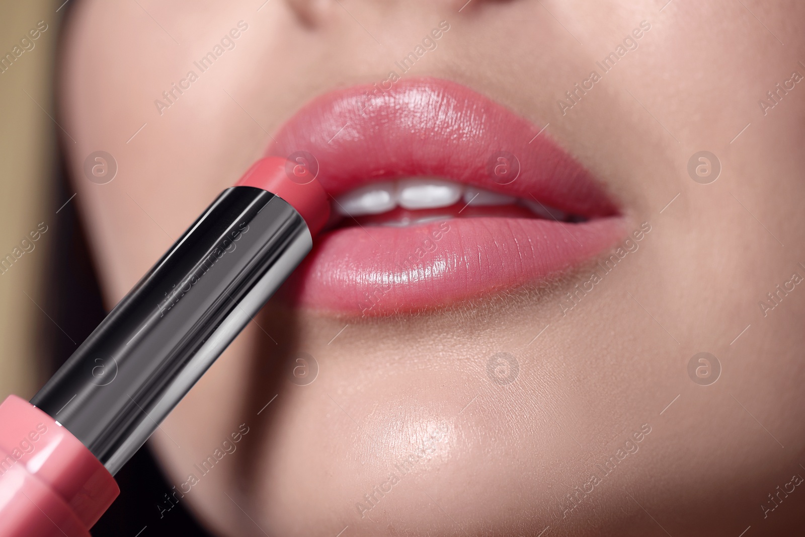 Photo of Closeup view of young woman applying beautiful nude lipstick