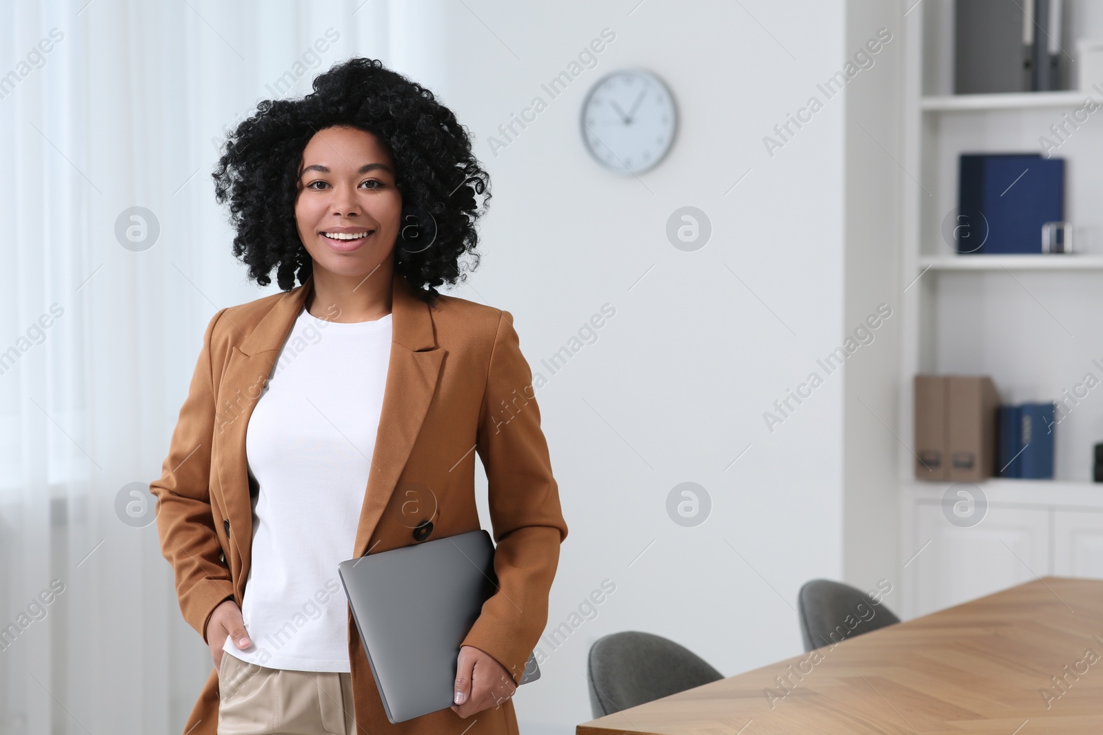 Photo of Smiling young businesswoman with laptop in modern office. Space for text