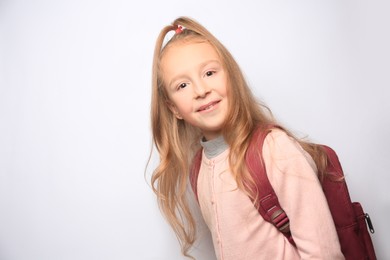 Photo of Happy little girl with backpack on white background. Space for text