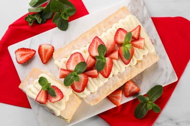 Photo of Delicious cake roll with strawberries and mint on white table, flat lay