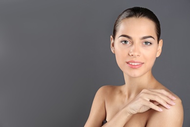 Portrait of beautiful young woman and space for text on grey background. Cosmetic surgery concept