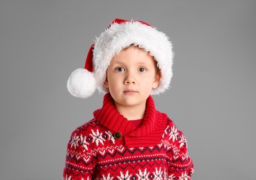 Photo of Cute child in Santa hat on grey background. Christmas celebration