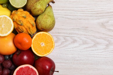 Many different fresh fruits on light wooden table, flat lay. Space for text