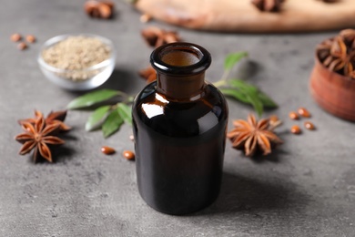 Photo of Bottle of essential oil and anise on grey table