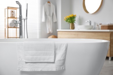 Photo of Fresh white towels on tub in bathroom