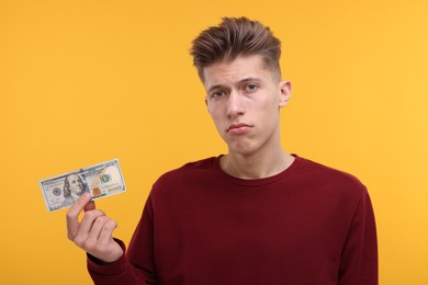 Photo of Upset man with dollar banknote on yellow background