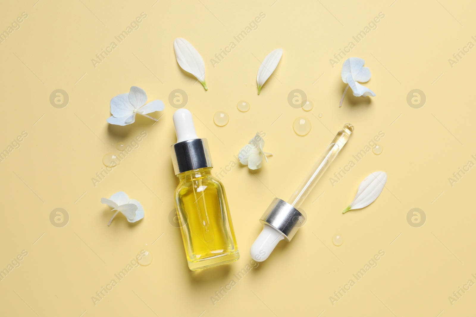 Photo of Bottle of cosmetic serum, pipette and beautiful flowers on pale yellow background, flat lay