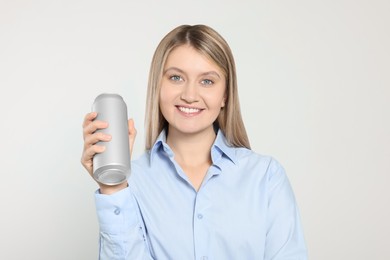 Beautiful happy woman holding beverage can on light background