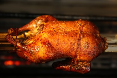 Photo of Grilling whole delicious duck in rotisserie machine, closeup