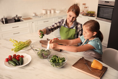 Mother and daughter cooking salad together in kitchen