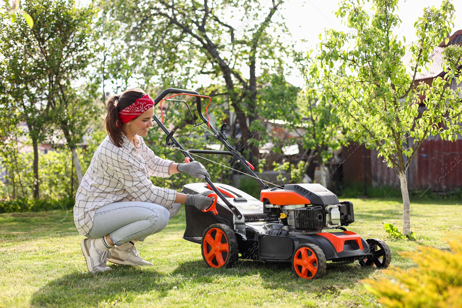 Photo of Smiling woman with lawn mower in garden on sunny day