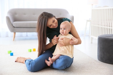 Photo of Young mother with cute baby girl at home