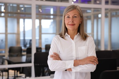 Photo of Smiling woman with crossed arms in office, space for text. Lawyer, businesswoman, accountant or manager