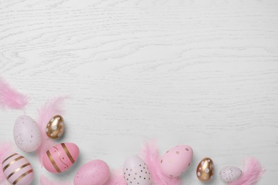 Flat lay composition with festively decorated Easter eggs on white wooden table. Space for text