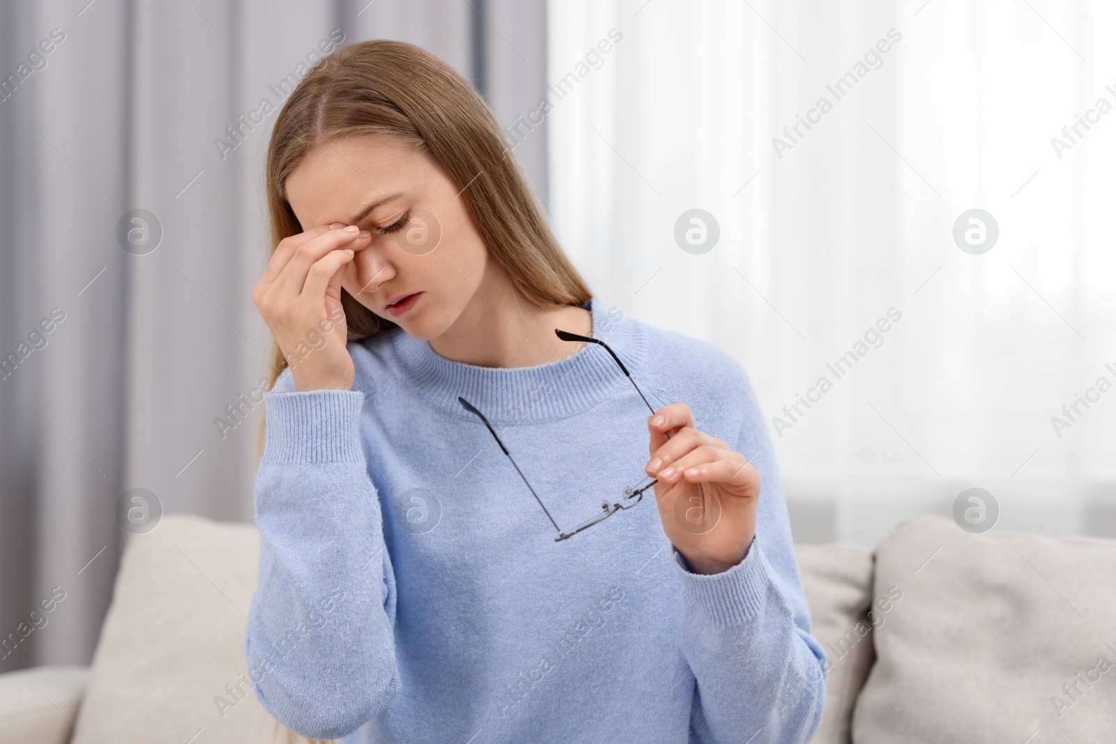 Photo of Overwhelmed young woman with glasses suffering from headache at home