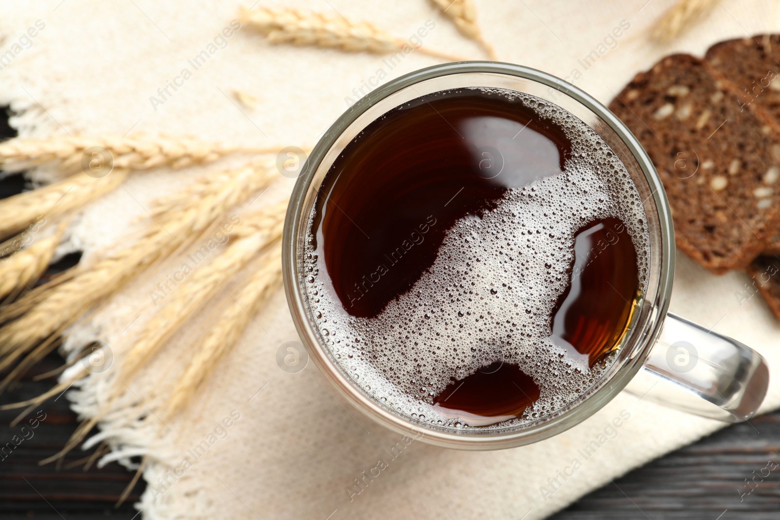 Photo of Mug of delicious kvass, spikes and bread on table, flat lay