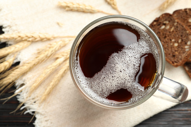 Mug of delicious kvass, spikes and bread on table, flat lay