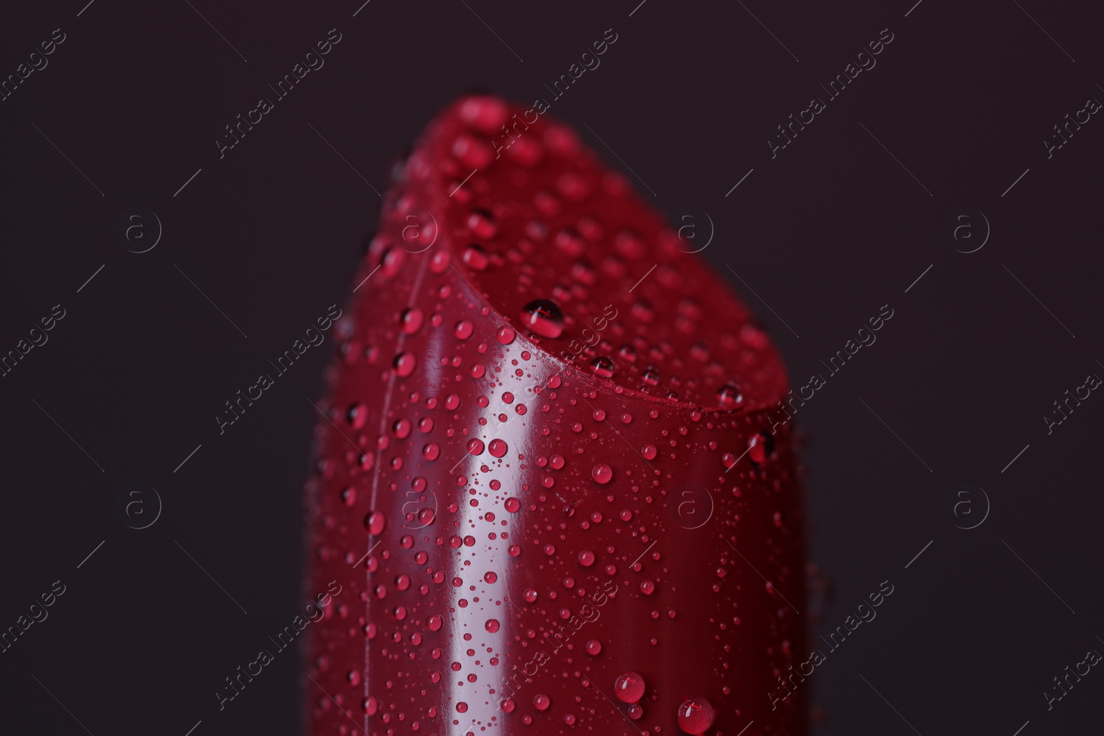 Photo of Beautiful red lipstick with water drops on dark background, macro view